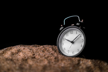 waste time ideas concept with sand and black alarmclock black background