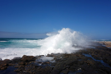 Fototapeta na wymiar Welle bricht auf Felsen