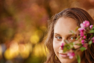 Fototapeta premium Portrait of a beautiful smiling girl with beautiful long hair in spring garden.