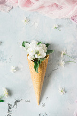 Flowers in a waffle cone on a gray background with a pink textile