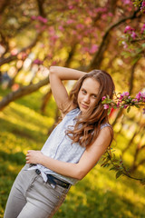 Portrait of a beautiful smiling girl with beautiful long hair in spring garden.