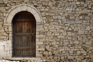 Stone wall with old wooden door in Old town Berat, Albania 