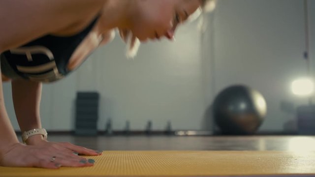 Blond Sporty Young Lady is Doing Push Ups in the Gym during Training