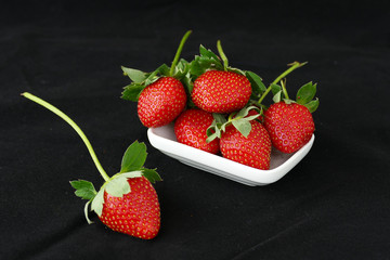 very fresh strawberries in white plate on a black background,

