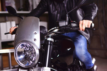 Closeup of motorcycle headlamp. Biker is preparing to leave the garage.