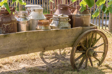 Alte Kutsche mit Milchkannen beladen als Dekoration auf einem Bauernhof