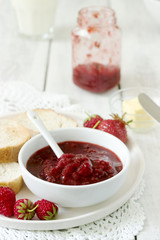 Strawberry jam in a glass jar and toast with butter and jam. Rustic style.