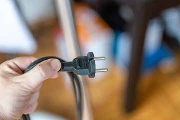 Junger Mann rollte Kabel vom Staubsauger zusammen