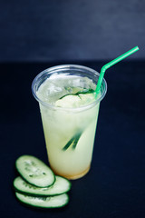 Cucumber lemonade in plastic cup on the black background