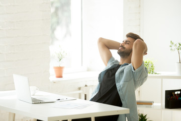 Smiling relaxed worker leaning back in chair, calm and happy satisfied with finished work. Cheerful manager resting with eyes closed during break, relieving stress and controlling emotions, task done
