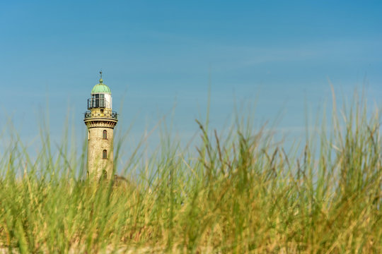 Leuchtturm in Warnemünde mit Gräsern des Ostseestrandes im Vordergrund