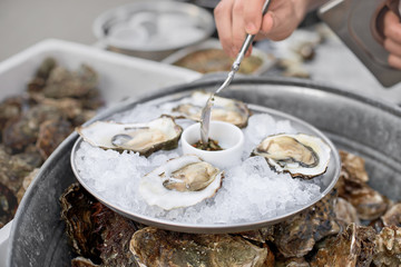Close Up of Server with Tray of Fresh Shucked Oysters with Lemon Wedges Served as Appetizer