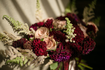 Wedding disheveled bouquet with claret dahlias, cream roses and greens. Close photo