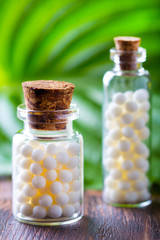 Homeopathy pills bottle wooden eco green leaf background
