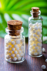 Homeopathy pills bottle wooden eco green leaf background
