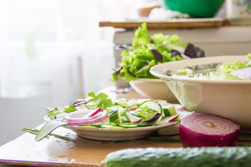 Preparing salad at home kitchen with radish, lettuce,red onion and basil leaves. Diet or vegetarian food concept