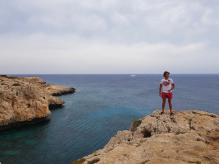 View to the sea, Cyprus, Protaras, May 2018. Beautiful blue sea. Rocks and mountains. It takes breath from this spectacle. A man stands on the edge of a rock and looks at this beauty