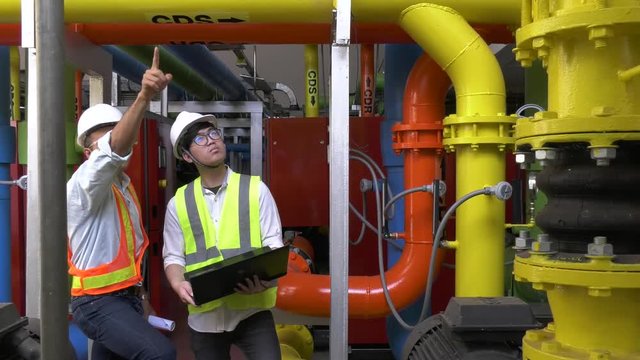 Asian engineer wearing glasses working in the boiler room,maintenance checking technical data of heating system equipment,Thailand people	