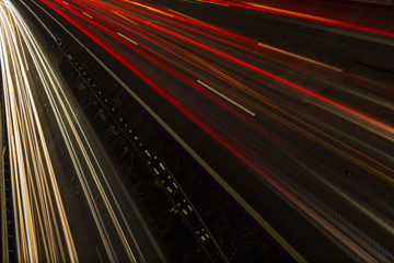 Fototapeta na wymiar Night scene of motion blurred light tracks glowing to the darkness of highway traffic to the city just after sunset. Creative long time exposure diagonal composed photography.