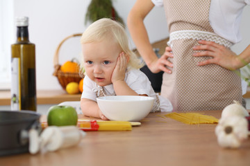Mother and little daughter  cooking in the kitchen. Spending time all together or happy family concept