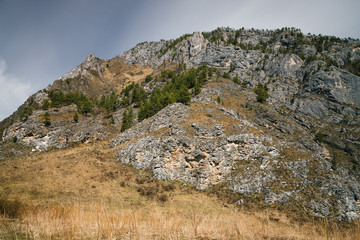 Beautiful rocky green mountain with greenery. Natural textured background with rock and sky.