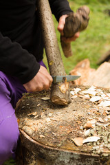 Using a fixed blade knife to sharpen a thick branch into a camp tool