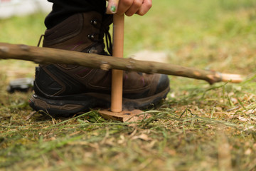 Woman using knife and dry materials with friction bow to start a fire in the forest