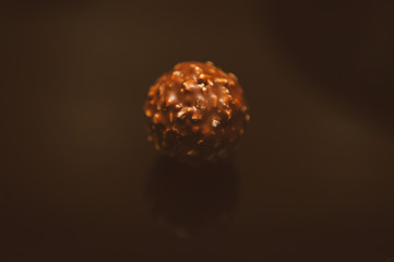 Chocolate ball. Chocolate ball candy coated with hazelnuts, composition isolated over the black background. Chocolate . food and style