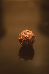 Chocolate ball. Chocolate ball candy coated with hazelnuts, composition isolated over the black background. Chocolate . food and style