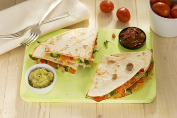 Vegetable quesadillas with broccoli, peppers, tomato, peppers and cheese with guacamole and tomato dip. 