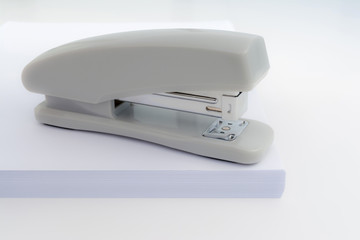 gray stapler is located on a pile of white paper, abstract chancery background