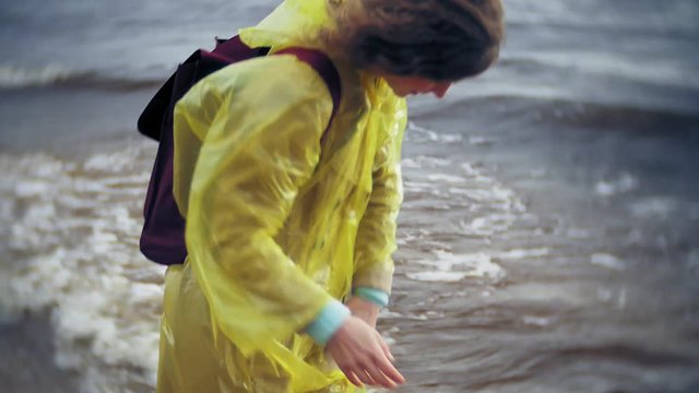 Happy woman walking along the coast Traveling Lifestyle adventure vacation outdoors. A girl dressed in a fashionable yellow raincoat