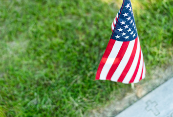 A single American flag placed at a veteran's gravesite marker