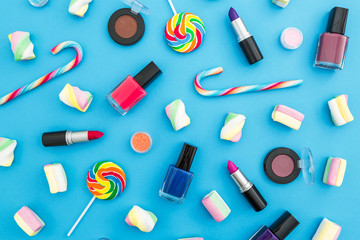 Composition with female cosmetics and bright candy on blue background. Top view. Flat lay. Creativity feminine desk.