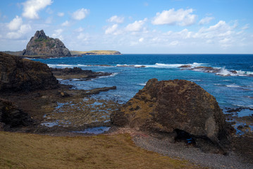 Raquel's Hole, a holed rock at the Island of Fernando de Noronha, Pernambuco, Brazil. The natural pools behind it are a sharks nursery. The Sela Gineta and Rata Islands are visible in the background