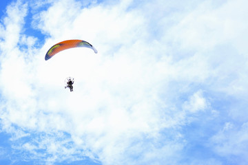 Paraglider flying in the blue sky against the background of clouds