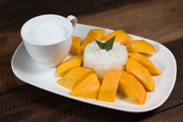 mango sticky rice or Khaoniao mamuang on a wooden table, a traditional thai dessert made with glutinous rice,fresh mango and coconut milk