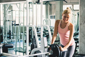 Fototapeta premium Woman doing and lifting dumbbell for weight training at sport gym with happy and smile, gym workout concept