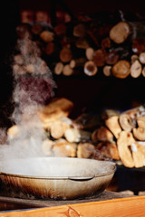 Closeup photo of steaming pot with food heated on fire. focusing on the front edge of the pot.