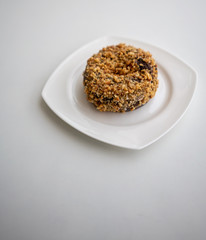 Single ground peanut coated on chocolate flour donut on white plate isolated on white
