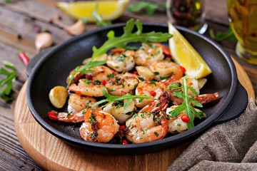 Prawns Shrimps roasted in garlic butter with lemon and parsley on wooden background. Healthy food.