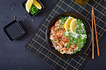 Rice with young green peas, shrimps and arugula in black bowl. Healthy food. Buddha bowl. Top view. Flat lay