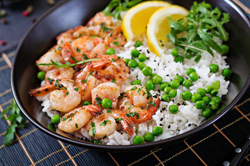 Rice with young green peas, shrimps and arugula in black bowl. Healthy food. Buddha bowl
