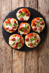 Summer food: hot eggplant with cheese, tomatoes, sausage and sauce close up on a slate board. Vertical top view