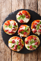 Pizza from baked eggplants with mozzarella, tomatoes, sausages and greens close-up. Vertical top view