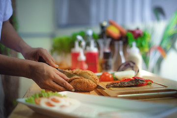 french bread burger being cooks by chef, cutting sliced in piece for meat filling in loaf
