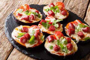 Summer food: hot eggplant with cheese, tomatoes, sausage and sauce close up on a slate board. horizontal