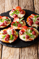 Pizza from baked eggplants with mozzarella, tomatoes, sausages and greens close-up. vertical