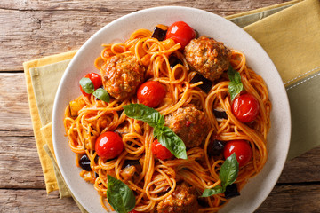 Spaghetti with meat balls, vegetables in a tomato sauce close-up on a plate on a table. horizontal top view, rustic