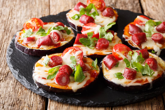 Delicious aubergines with mozzarella cheese, tomatoes, sausages and sauce close-up on a slate board. horizontal